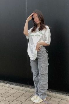 a woman standing in front of a black wall with her hands on her head and looking at the camera