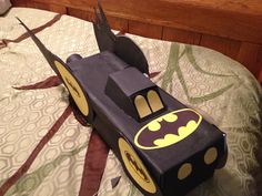 a paper car made to look like batman on top of a bed with the bat symbol painted on it