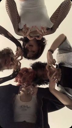 four people are standing in a circle holding wine glasses and looking up at the camera