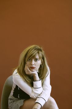 a woman sitting in a chair with her hand on her chin