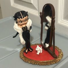 a cat figurine sitting next to a mirror on top of a table with a dog in front of it