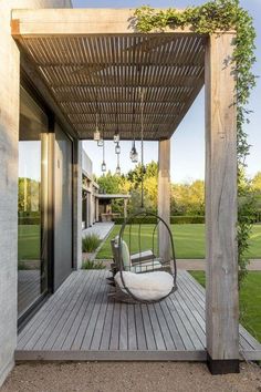 a porch with a swing chair on it and a wooden pergolan over the deck