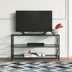 a flat screen tv sitting on top of a metal stand in front of a white wall