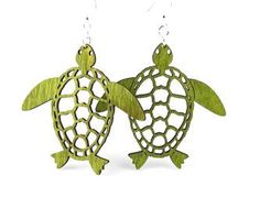 two green sea turtle shaped wooden earrings with laser cutouts on them, hanging from hooks