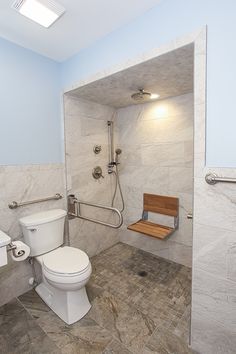 a bathroom with a toilet, sink and shower head mounted to the side of the wall