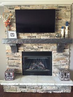 a fireplace with a flat screen tv mounted above it's mantle and two boxes on the side