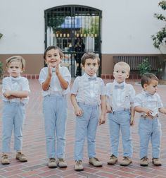 a group of young boys standing next to each other in front of a white building