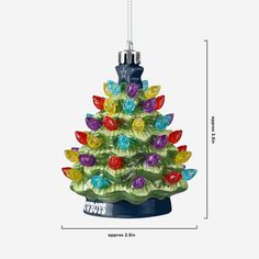 a glass christmas tree ornament with lights and ornaments on it's base