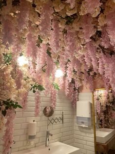 a bathroom with pink flowers hanging from the ceiling and a sink in front of it