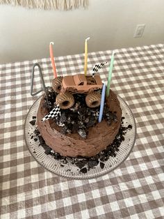 a birthday cake with candles on it sitting on top of a checkered table cloth