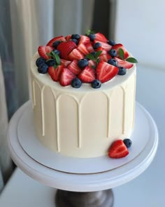 a white cake with strawberries and blueberries on top