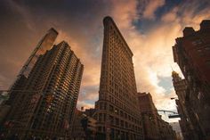 the sky is very cloudy and there are many tall buildings on this street in new york city