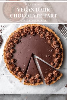 a chocolate tart pie with one slice missing from it and two forks next to it