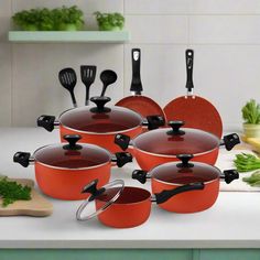 red pots and pans with black handles on a white counter