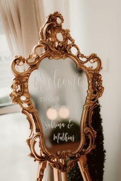 an ornate gold mirror with a welcome sign on it