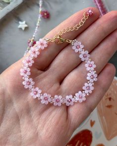 a hand holding a pink beaded bracelet on it's wrist with a gold chain