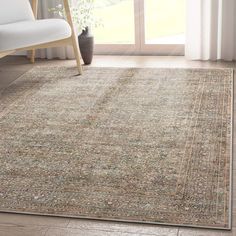 an area rug in a living room with a chair and large window overlooking the yard