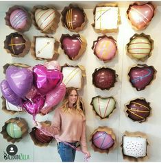 a woman standing in front of a wall with balloons and chocolates on the walls