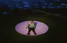 a man sitting on top of a pink circular object in the middle of a field