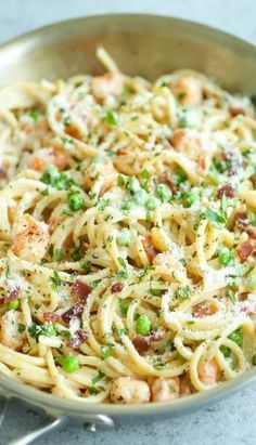 pasta with shrimp, peas and parmesan cheese in a bowl