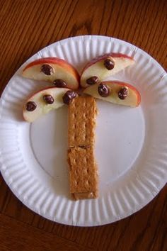 a paper plate topped with crackers and apples on top of a wooden table next to an apple slice