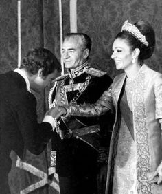 an old black and white photo of two people in formal wear shaking hands with one another