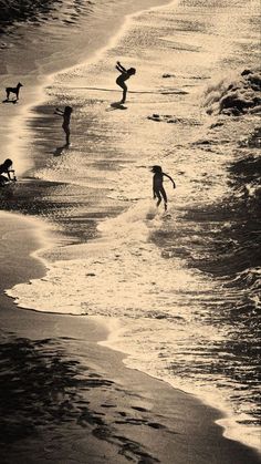 three people are playing in the water at the beach while one person is on their surfboard