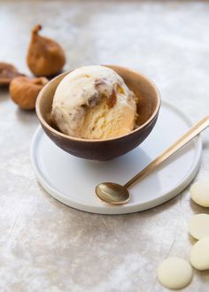 a bowl filled with ice cream sitting on top of a plate next to some nuts