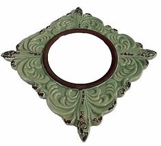 an ornate green mirror frame with a wooden circle in the center on a white background