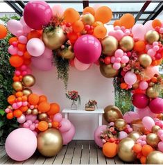 a room filled with lots of balloons and flowers on top of a wooden floor covered in greenery