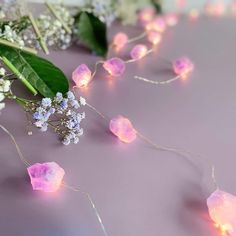 flowers and lights on a table with purple surface in the foreground, surrounded by greenery