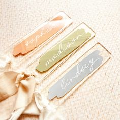 three hair clips with names on them sitting on a table next to some cloths