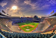 an empty baseball stadium filled with lots of seats under a blue sky and sun light