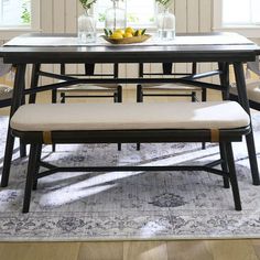 a dining table with four chairs and a bowl of fruit on top of the table