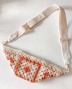 a crocheted purse with a white and red strap hanging from it's side