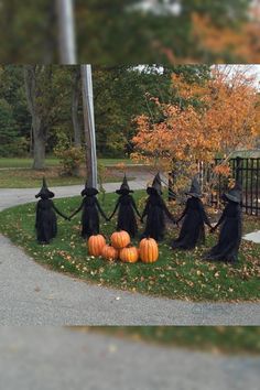 a group of witches holding hands with pumpkins in front of a gate and trees