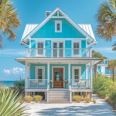 a blue house on the beach with palm trees in front of it and an ocean view