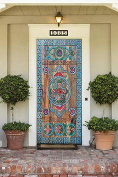 the front door to a house with potted plants on either side and an ornate wooden door