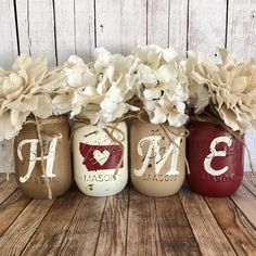 three mason jars with flowers in them sitting on a wooden table next to each other