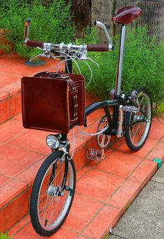 a bicycle with a brown leather case on the handlebars is parked in front of some plants