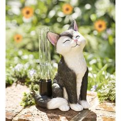 a cat figurine sitting on top of a rock next to a blender