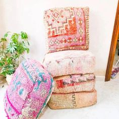 a pile of pillows sitting on top of a white floor next to a wooden mirror