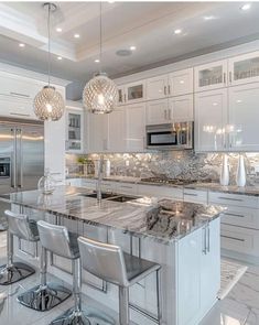 a kitchen with white cabinets and marble counter tops, stainless steel appliances and stools