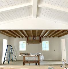 an unfinished room with white walls and wood beams