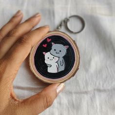 a hand holding a keychain with a bear and heart design on it's side