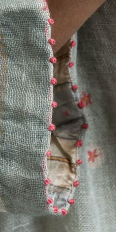 a woman's arm with a piece of fabric on it and some red flowers