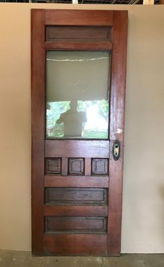 a dog is standing in front of a door with a glass pane on it's side