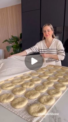 a woman standing in front of a baking sheet filled with cookies