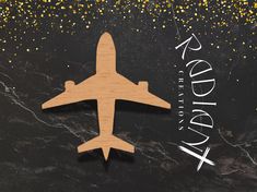 a wooden airplane with gold confetti around it on a black marble countertop