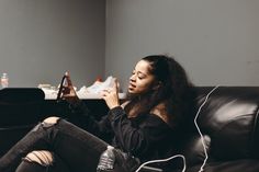 a woman sitting on top of a black couch holding a game controller in her hand